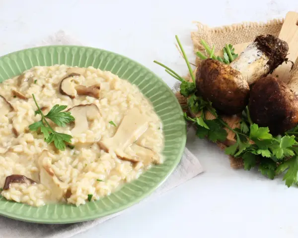 Piatto di cremoso risotto ai funghi, con funghi freschi e prezzemolo a guarnire. Un'ottima alternativa al risotto ai funghi surgelati.