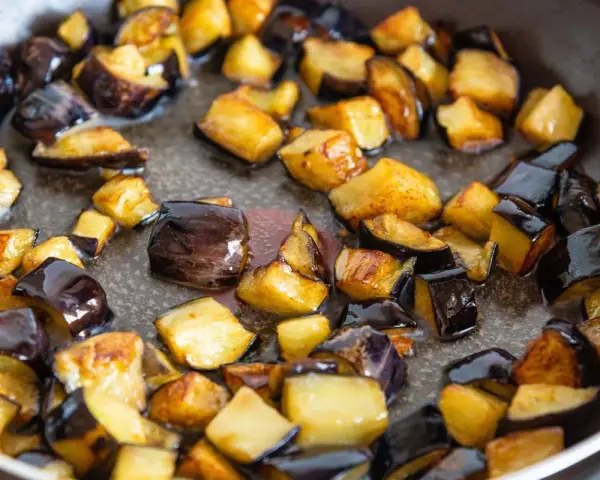 Melanzane a cubetti dorate e caramellate in padella, pronte per uno dei 100 modi per cucinare le melanzane.