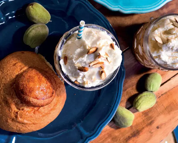 Deliziosa granita di mandorle servita con mandorle a lamelle e pane dolce. Freschezza siciliana in un bicchiere.
