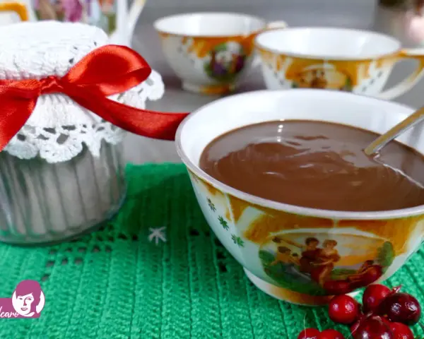 Un vasetto decorato con un fiocco rosso e una tazza piena di cioccolata fatta in casa, pronta per essere gustata.