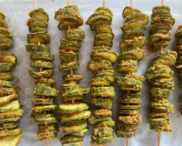 Spiedini di zucchine al forno, dorati e croccanti, pronti per essere gustati.