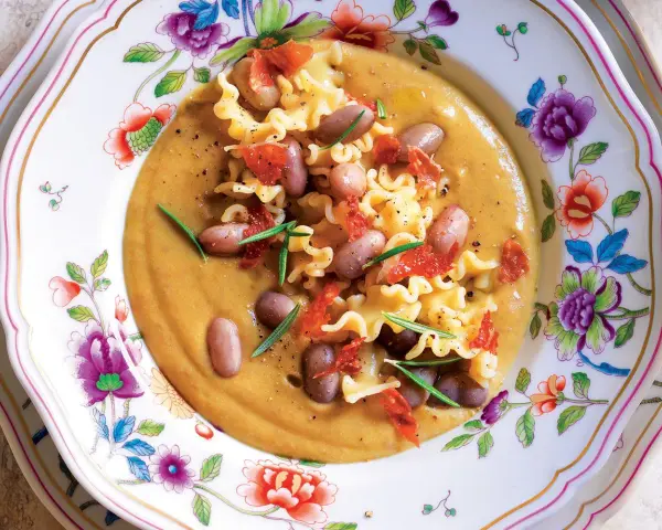 Un piatto invitante di pasta e fagioli, con pasta riccia, fagioli borlotti, pomodori secchi e rosmarino. La ricetta originale è un classico confortante.