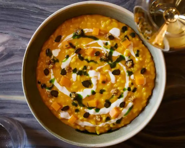 Risotto cremoso alla zucca Hokkaido, guarnito con cubetti di zucca, semi tostati e un filo di panna. Un'idea per le tue ricette zucca hokkaido.