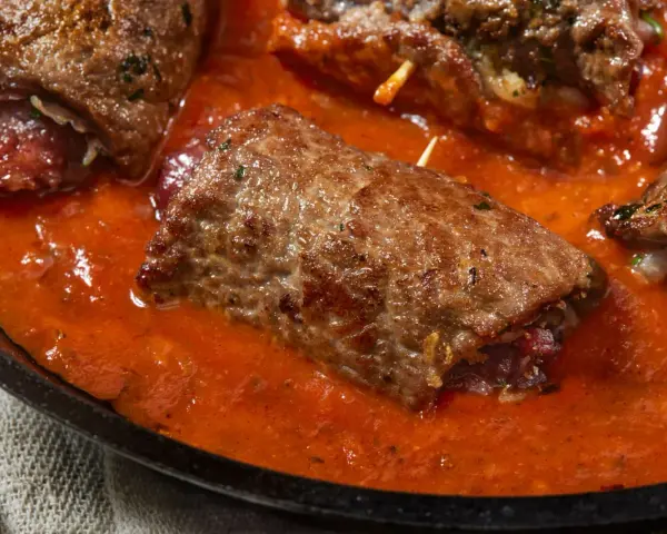 Involtini di carne in padella con sughetto rosso, un piatto succulento e invitante.