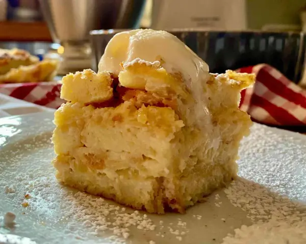 Una fetta di torta di pane raffermo mele e uvetta, cosparsa di zucchero a velo e sormontata da una pallina di gelato.