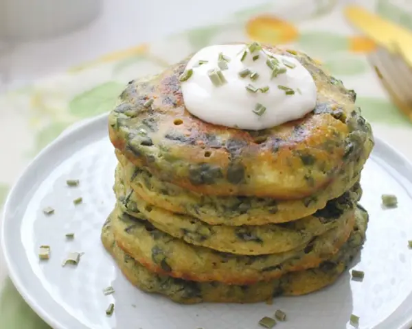 Pancakes salati con farina di grano saraceno e spinaci, guarniti con panna acida e erba cipollina. Un'idea gustosa per le tue ricette con farina di grano saraceno.
