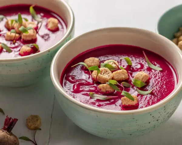 Zuppa cremosa di barbabietola rossa, guarnita con crostini e germogli. Un'idea per le tue barbabietola rossa ricette.