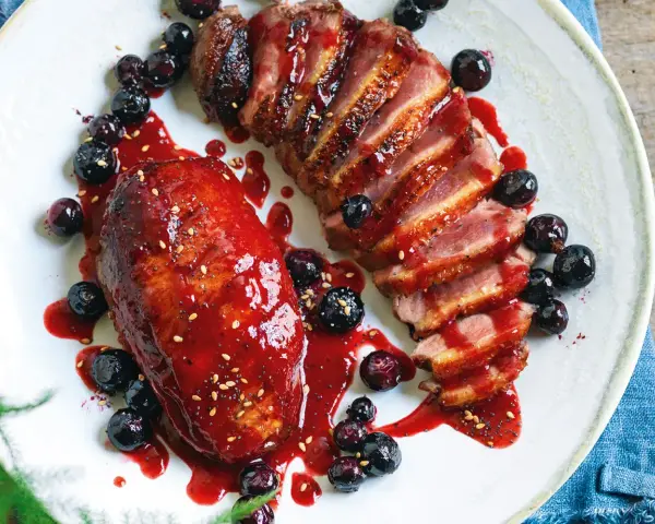 Petto d'anatra ricette: succulento petto d'anatra affettato, glassato con salsa ai frutti di bosco e guarnito con mirtilli freschi.