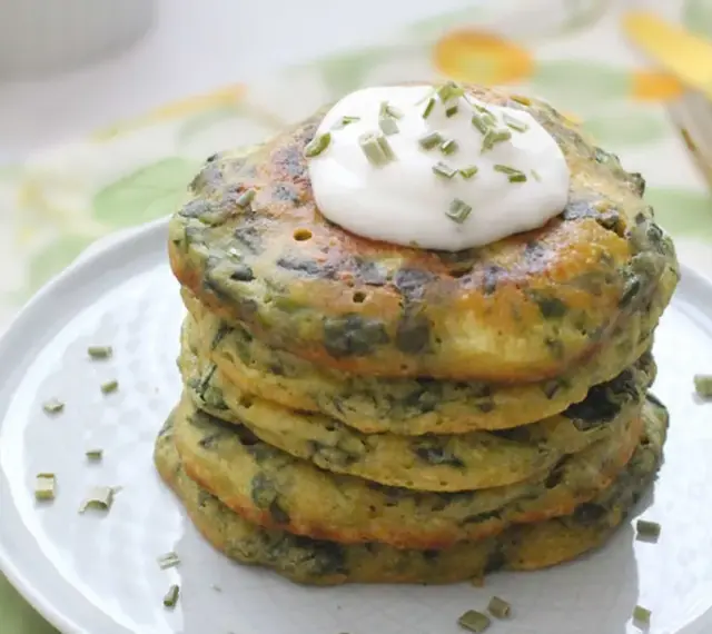 Pancakes salati con farina di grano saraceno e spinaci, guarniti con panna acida e erba cipollina. Un'idea gustosa per le tue ricette con farina di grano saraceno.