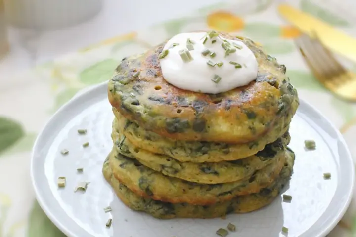 Pancakes salati con farina di grano saraceno e spinaci, guarniti con panna acida e erba cipollina. Un'idea gustosa per le tue ricette con farina di grano saraceno.