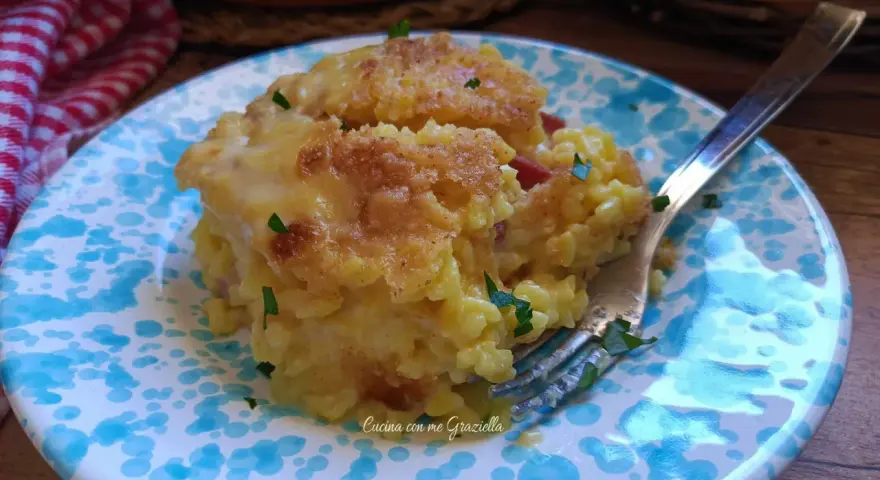 Sformato di riso dorato e filante, servito su un piatto con decorazioni blu. Un piatto invitante e gustoso.