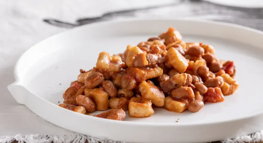 Un piatto di pisarei piacentini, pasta fatta in casa con fagioli e pomodoro, un assaggio della ricetta originale.