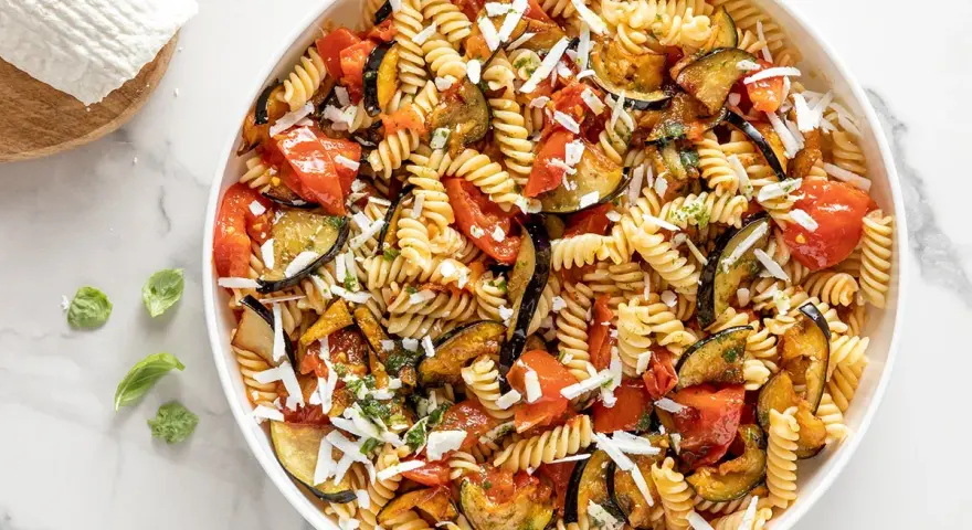 Pasta fredda con melanzane, pomodori e ricotta salata grattugiata. Un'idea perfetta per cosa mettere nella pasta fredda, fresca e saporita.