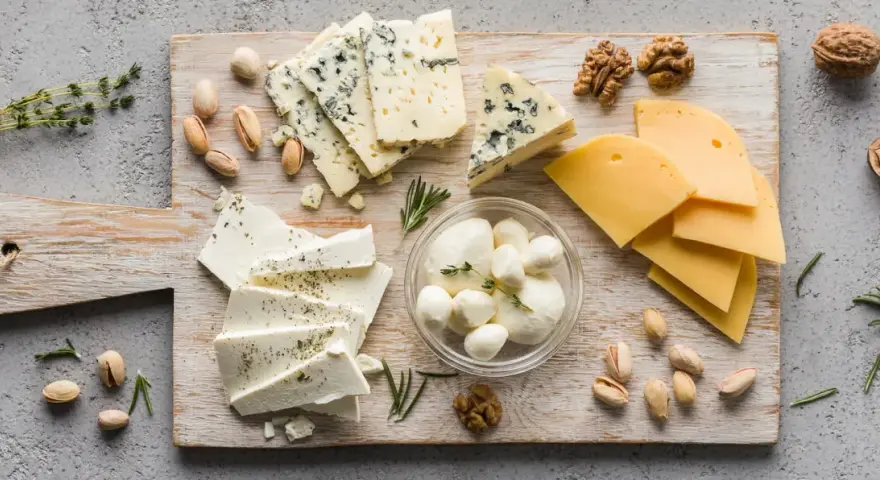 Assortimento di formaggi freschi: mozzarelline, feta e formaggi stagionati, con noci e pistacchi.