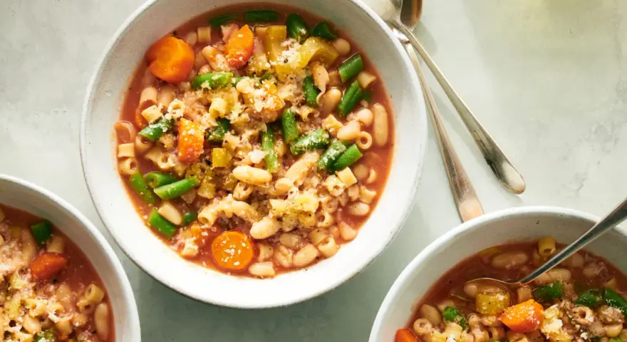 Tre ciotole di fumante pasta e fagioli vegetariana, ricca di verdure e condita con parmigiano.