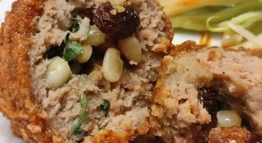 Polpette al sugo napoletane, un abbraccio di carne saporita con pinoli e uvetta, immerse in un sugo rosso invitante.