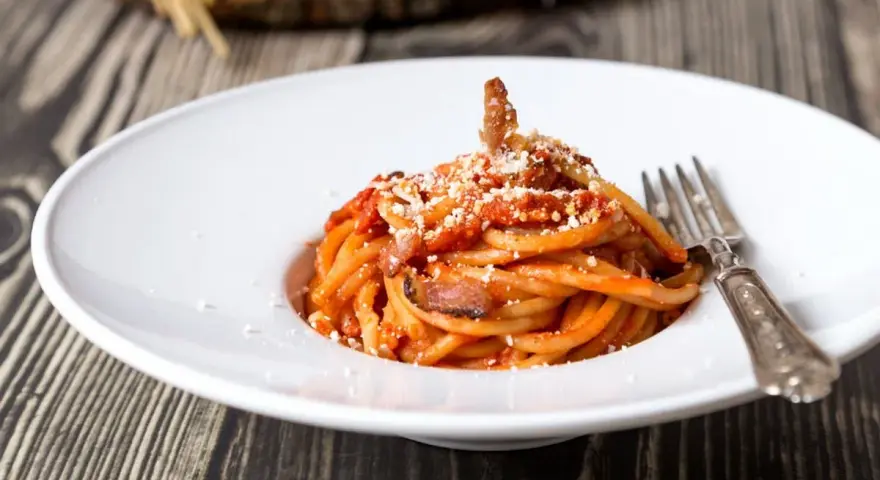 Piatto di spaghetti con sugo rosso, guanciale e formaggio grattugiato. Una gustosa ricetta originale amatriciana cipolla.