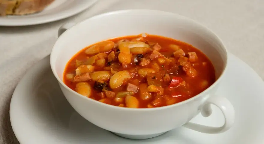 Fagioli in umido, una ricetta veneta saporita con fagioli bianchi, pancetta e pomodoro, serviti in una ciotola bianca.