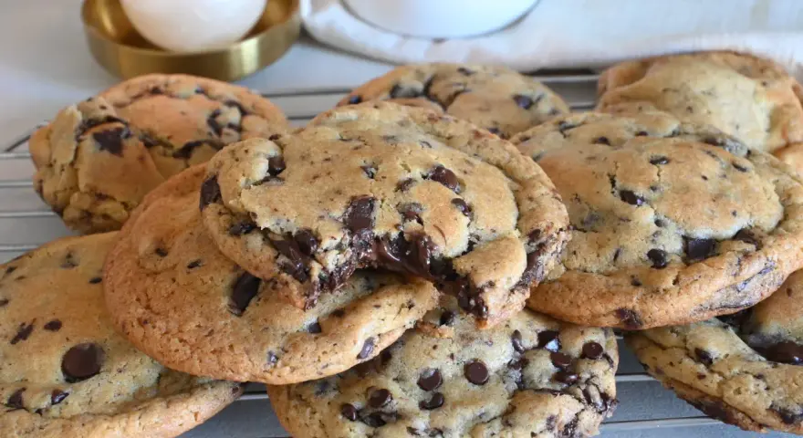 Biscotti cookies al cioccolato, appena sfornati e ancora caldi, con gocce di cioccolato fondente che si sciolgono. Una ricetta perfetta per una pausa golosa.