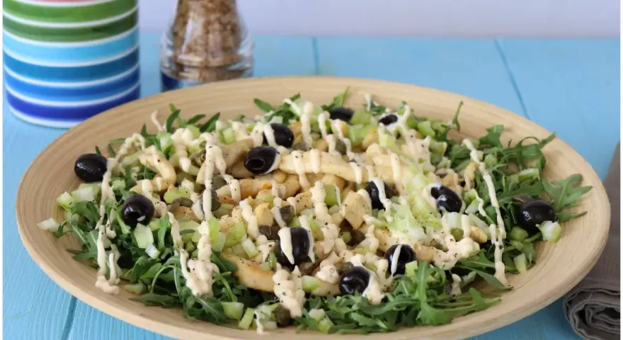 Deliziosa insalata di pollo con rucola, sedano, olive nere e capperi, condita con una cremosa salsa.