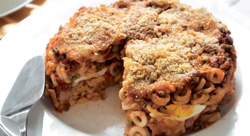 Un invitante anelletti al forno, dorato e croccante, con strati di pasta, ragù, piselli e uova sode.