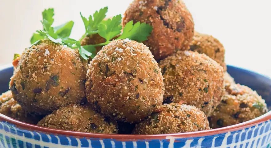 Polpette dorate e croccanti, perfette per le tue ricette con melanzane. Guarnite con prezzemolo e basilico fresco.