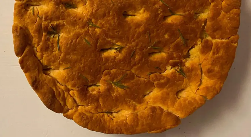 Focaccia di lenticchie dorata e fragrante, con rosmarino fresco che spunta dalla crosta croccante.