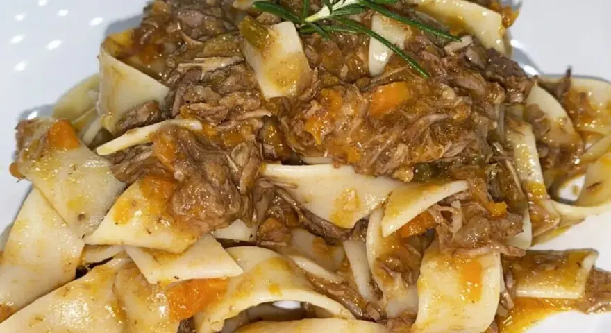 Pappardelle condite con un saporito ragù di cinghiale in bianco, guarnite con rosmarino fresco.
