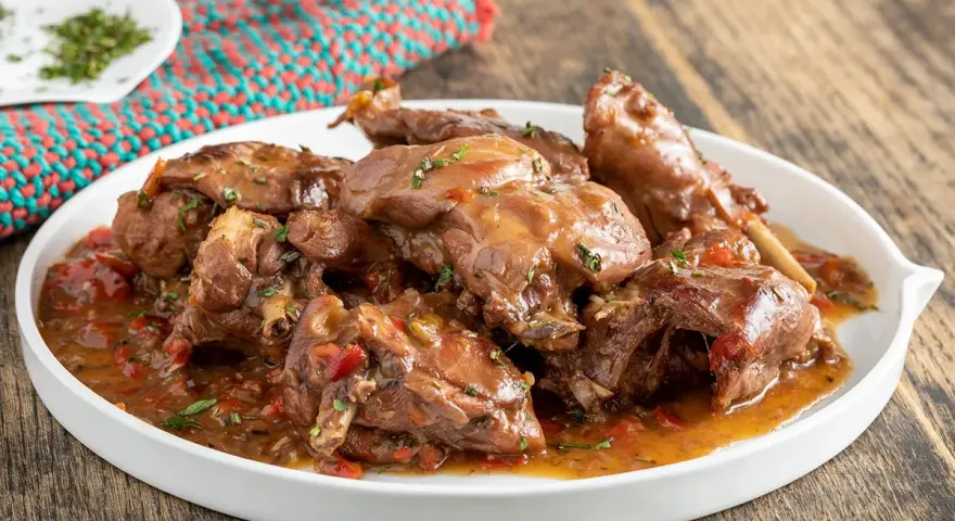 Piatto di coniglio con peperoni rossi e verdi, cotto in umido con erbe aromatiche.