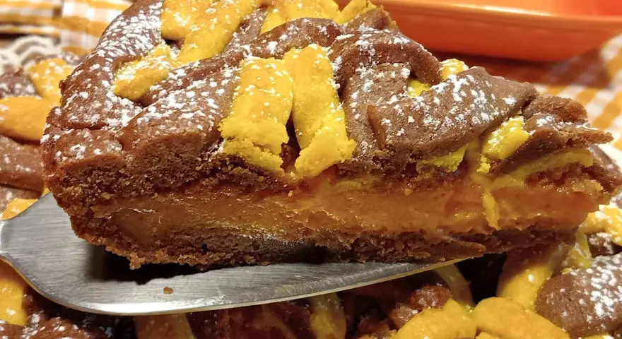 Fetta di torta con ripieno cremoso e decorazioni a griglia, uno dei tanti dolci con albicocche che invitano ad essere assaggiati.