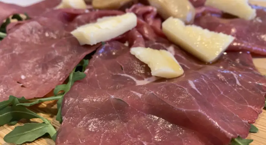 Carne salada cos'è? Fettine sottili di carne rossa, condite con erbe aromatiche e scaglie di formaggio stagionato, su un letto di rucola fresca.