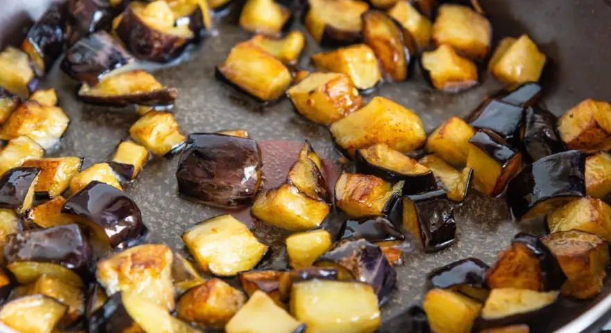 Melanzane a cubetti dorate e caramellate in padella, pronte per uno dei 100 modi per cucinare le melanzane.