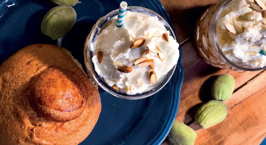 Deliziosa granita di mandorle servita con mandorle a lamelle e pane dolce. Freschezza siciliana in un bicchiere.