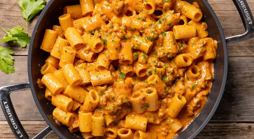 Un invitante piatto di pasta con salsiccia alla napoletana, condita con una cremosa salsa arancione e prezzemolo fresco.