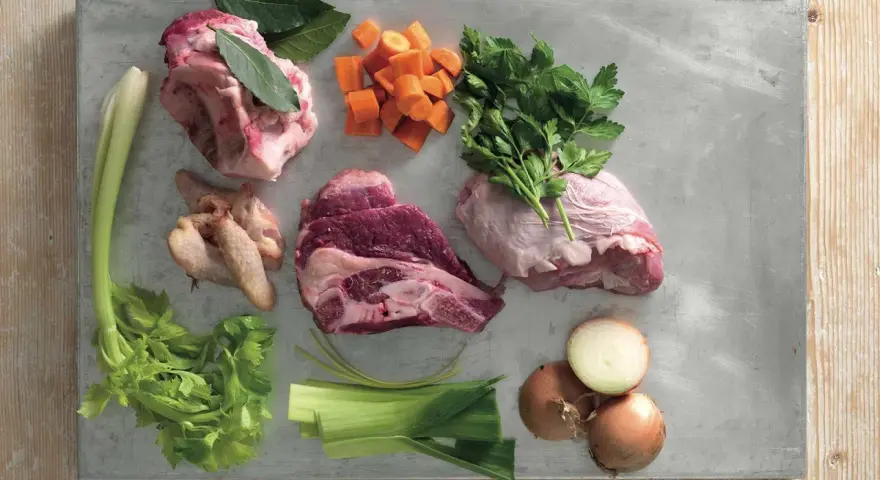 Ingredienti per un brodo saporito: carne per brodo, carote, sedano, cipolle, prezzemolo e alloro.