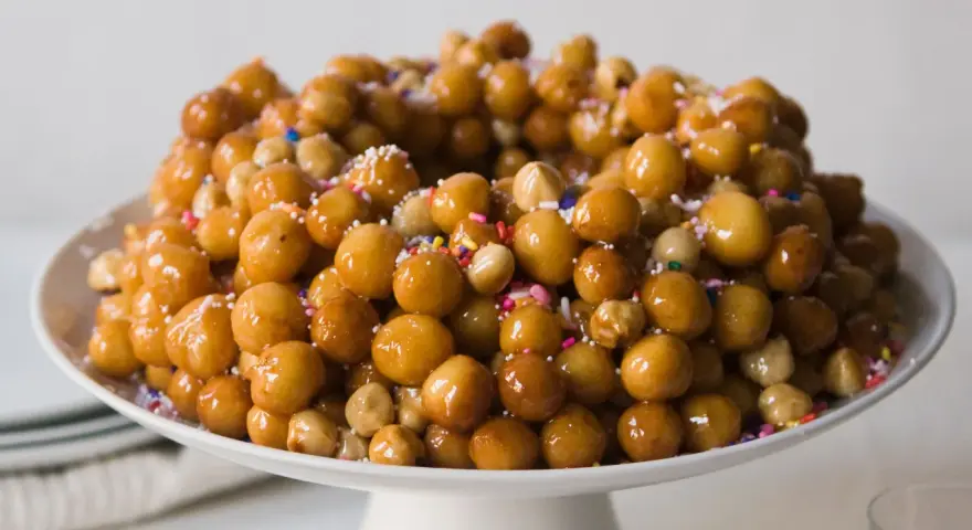 Struffoli ricetta della nonna: palline dorate e lucide, cosparse di zuccherini colorati, un dolce tradizionale che profuma di casa.