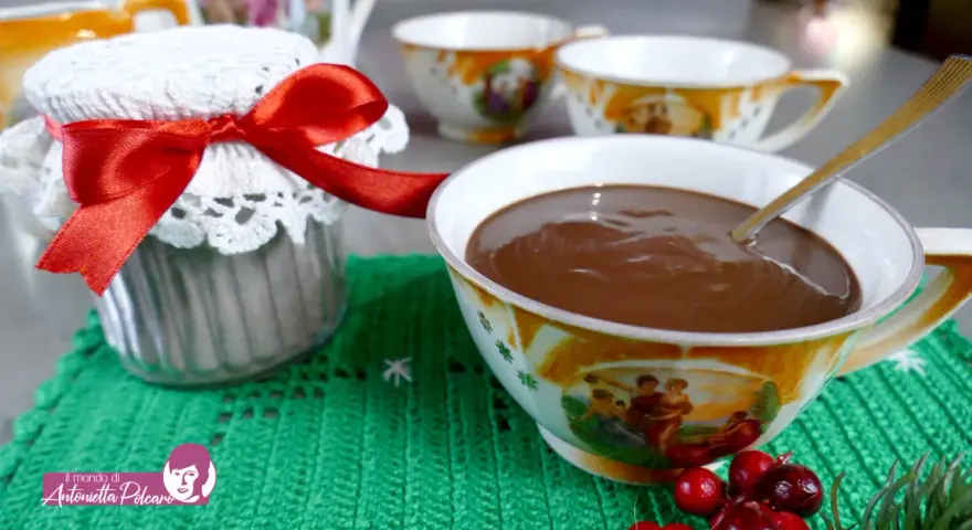 Un vasetto decorato con un fiocco rosso e una tazza piena di cioccolata fatta in casa, pronta per essere gustata.