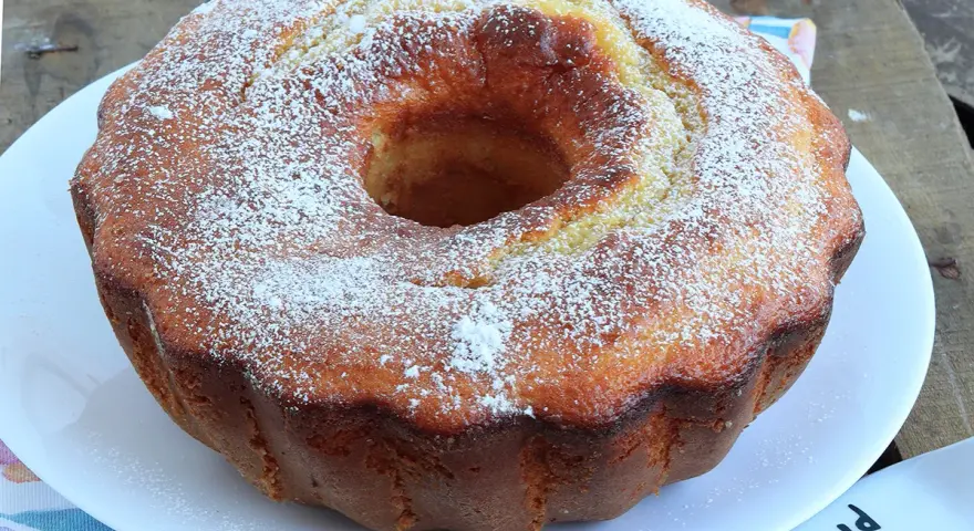 Ciambella soffice allo yogurt greco, cosparsa di zucchero a velo, pronta per essere gustata.