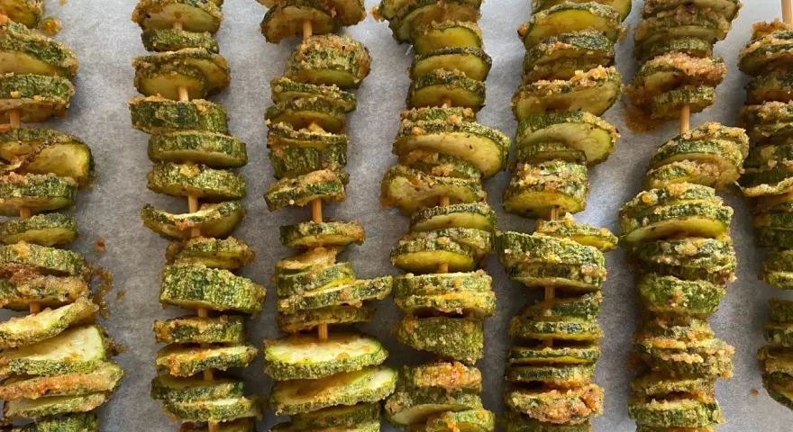 Spiedini di zucchine al forno, dorati e croccanti, pronti per essere gustati.