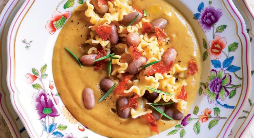 Un piatto invitante di pasta e fagioli, con pasta riccia, fagioli borlotti, pomodori secchi e rosmarino. La ricetta originale è un classico confortante.