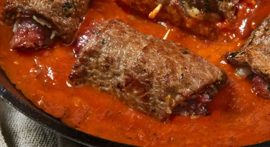Involtini di carne in padella con sughetto rosso, un piatto succulento e invitante.
