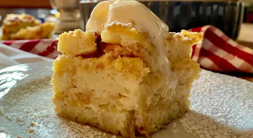 Una fetta di torta di pane raffermo mele e uvetta, cosparsa di zucchero a velo e sormontata da una pallina di gelato.