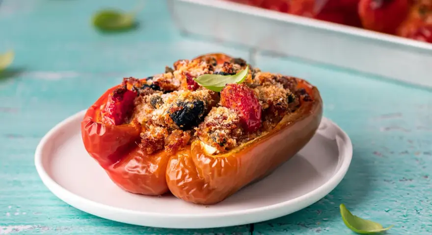 Peperoni ripieni, un classico delle ricette con peperoni, con un gustoso ripieno di pomodoro, olive e pangrattato, guarniti con basilico fresco.