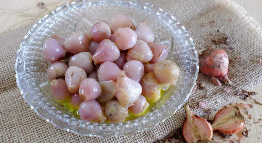 Lampascioni, piccoli bulbi rosa in una ciotola di vetro, sono un sapore pugliese da scoprire.