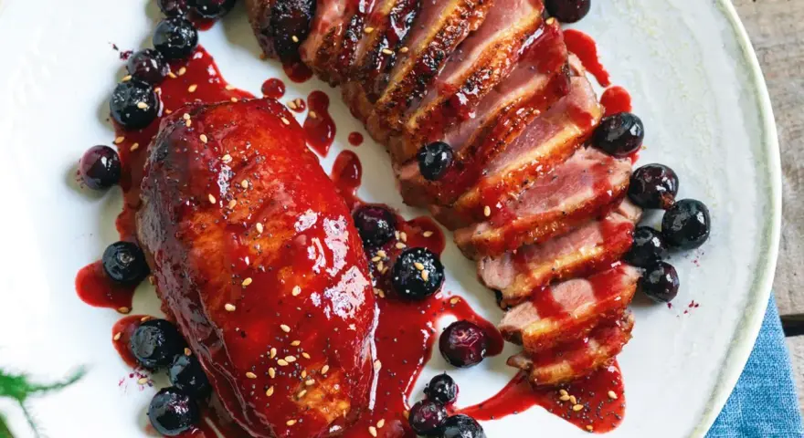 Petto d'anatra ricette: succulento petto d'anatra affettato, glassato con salsa ai frutti di bosco e guarnito con mirtilli freschi.