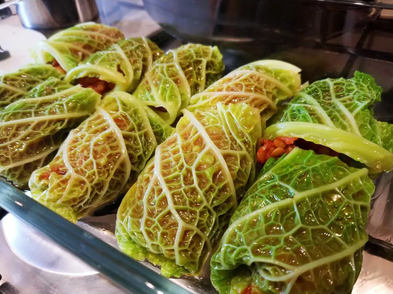 Involtini di cavolo cappuccio pronti per essere cotti, con un ripieno visibile.