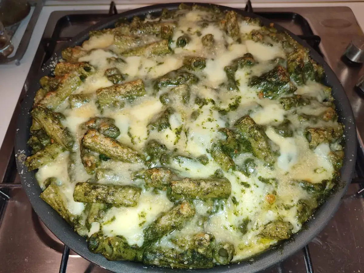 Pasta con salsiccia alla napoletana, un piatto ricco e saporito, cotto al forno con formaggio filante e un condimento verde intenso.