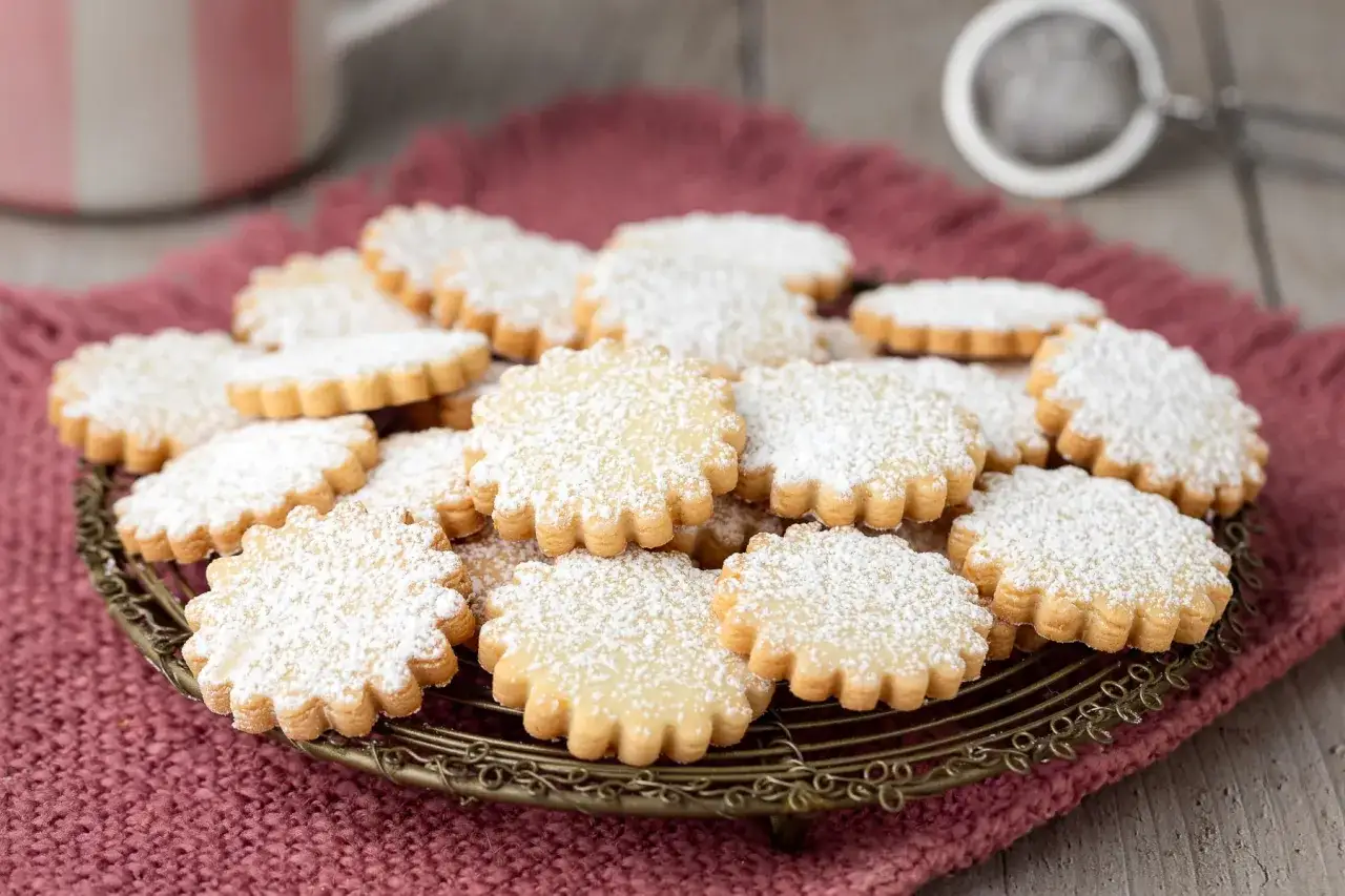 Deliziosi biscotti pasta frolla cosparsi di zucchero a velo, serviti su un vassoio decorato.