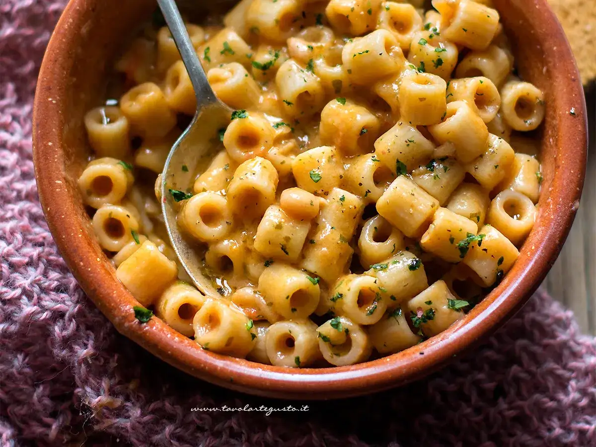 Un piatto fumante di pasta e fagioli vegetariana, con ditalini e fagioli bianchi in un sugo cremoso, guarnito con prezzemolo fresco.