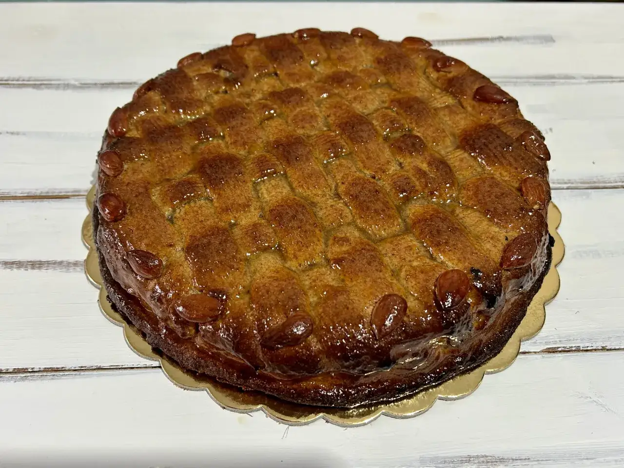 Deliziosa torta di mandorle siciliana con glassa lucida e mandorle intere sul bordo.